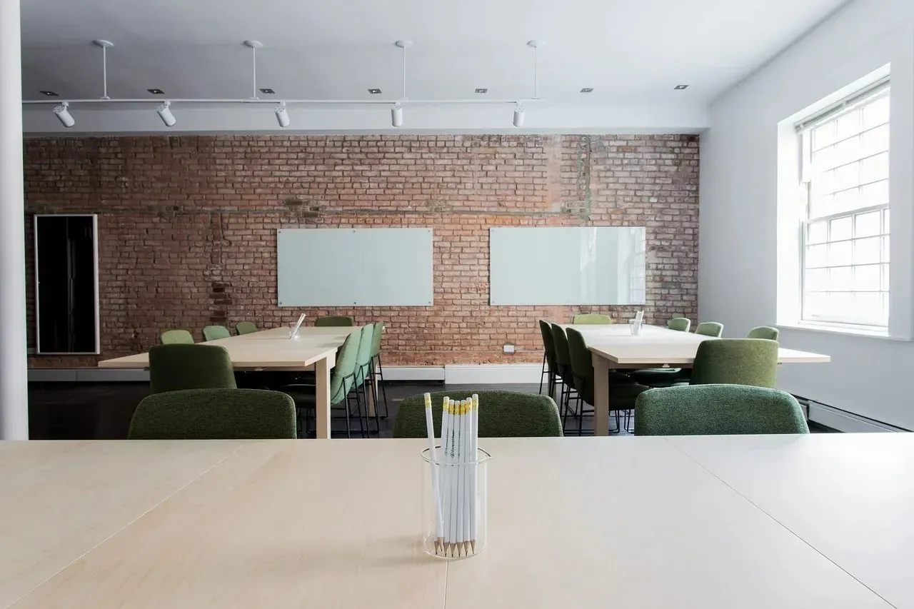 Modern office room with brick wall and green chairs