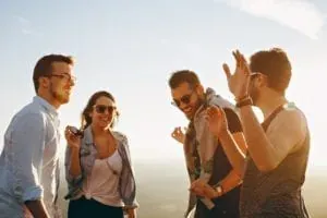 Four friends laughing outdoors at sunset
