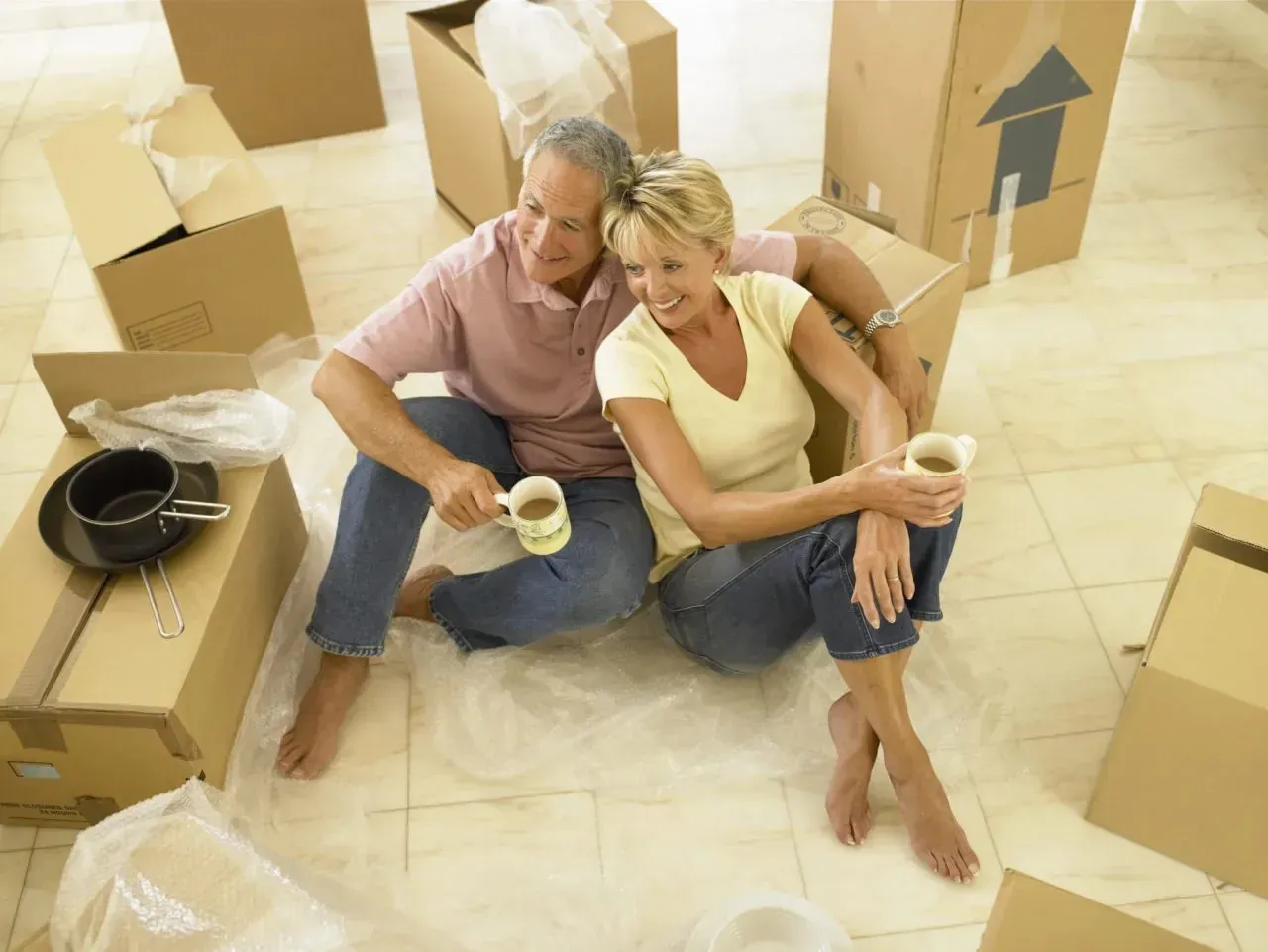 Mature couple drinking coffee among unbranded moving boxes