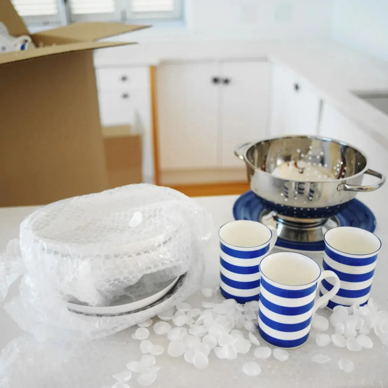 Bubble-wrapped dishes and striped mugs packed in kitchen