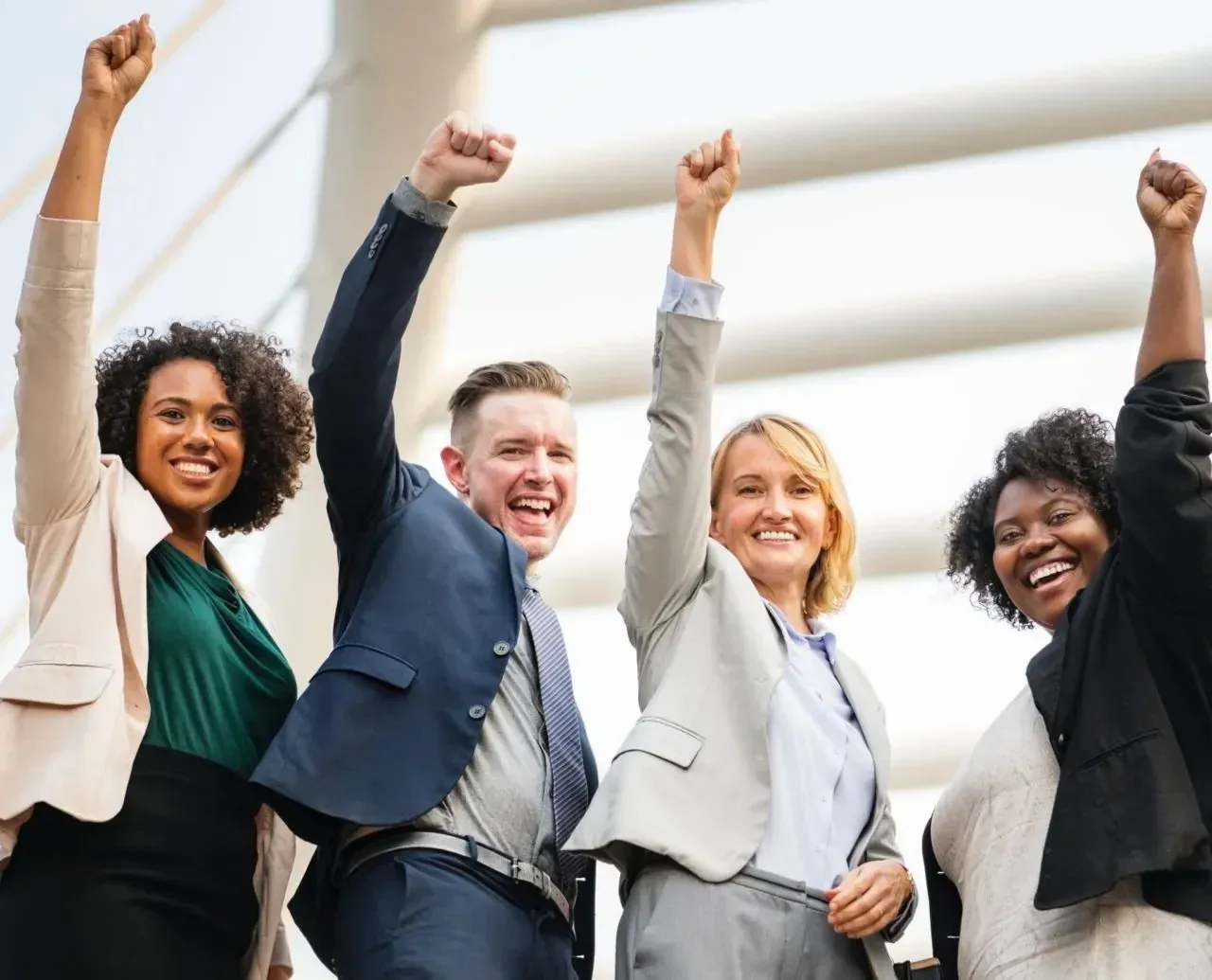 Four business colleagues celebrating with raised fists