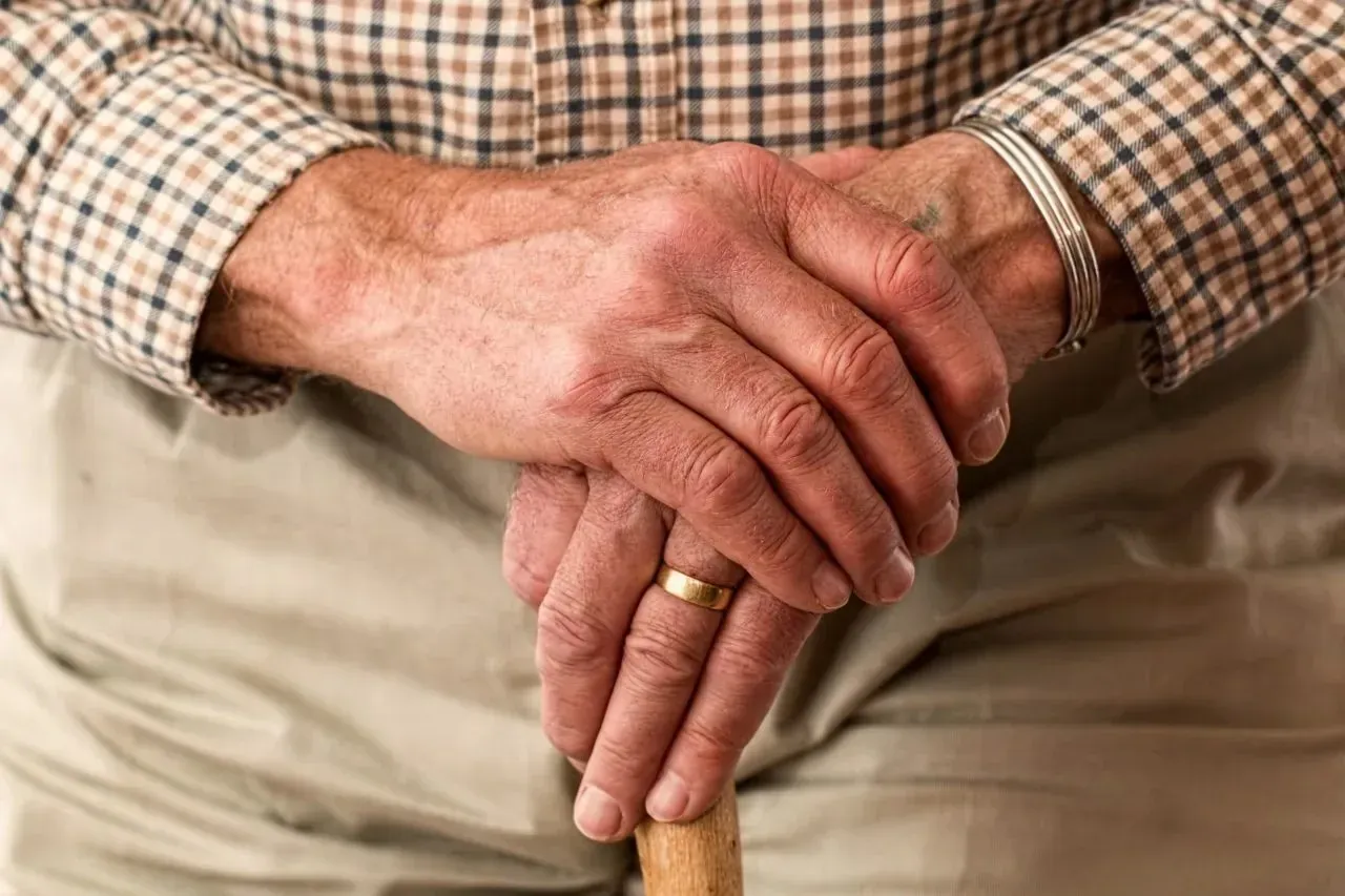 Elderly man's hands resting on walking cane