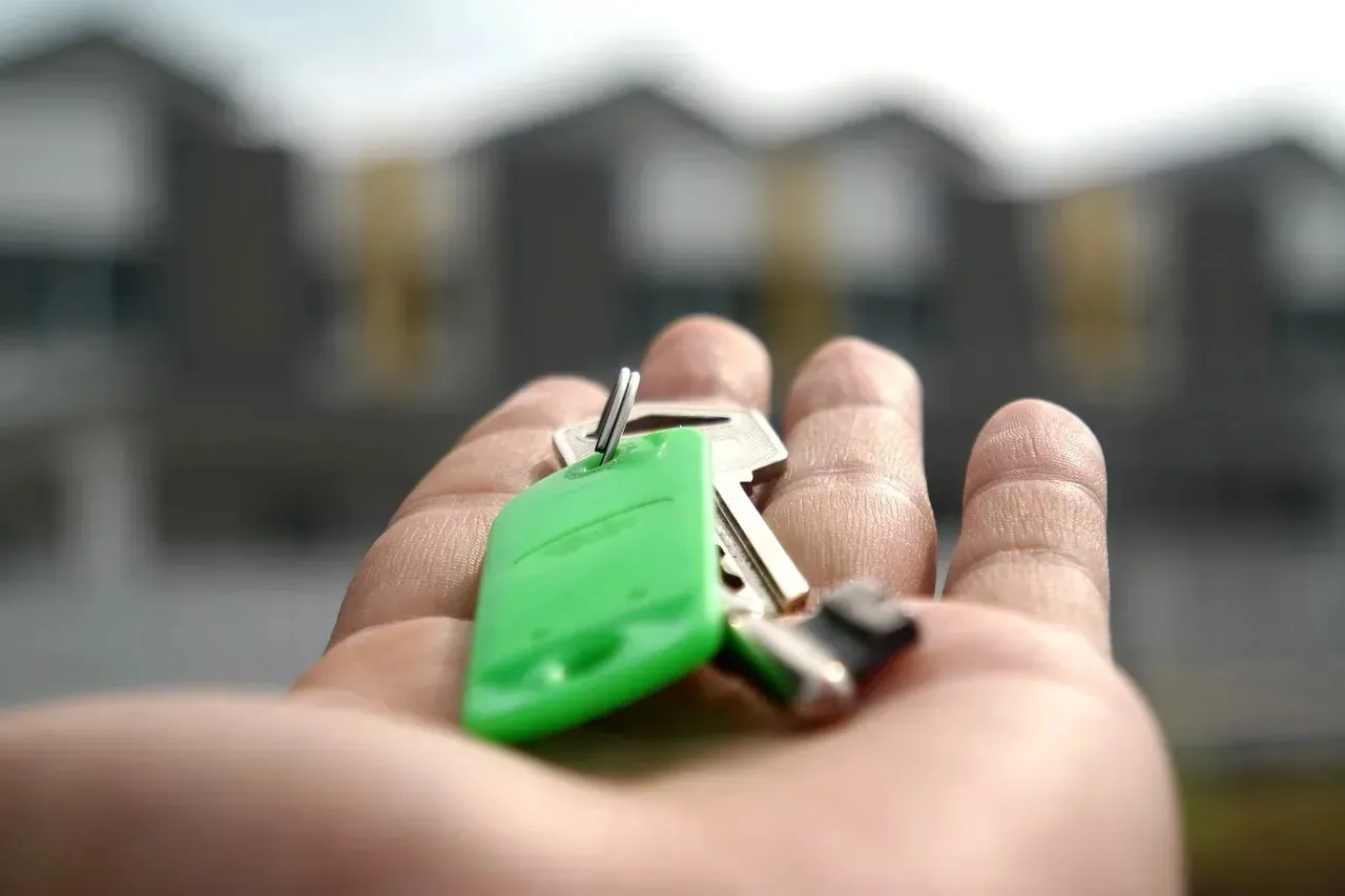Open hand holding house keys, blurred homes behind