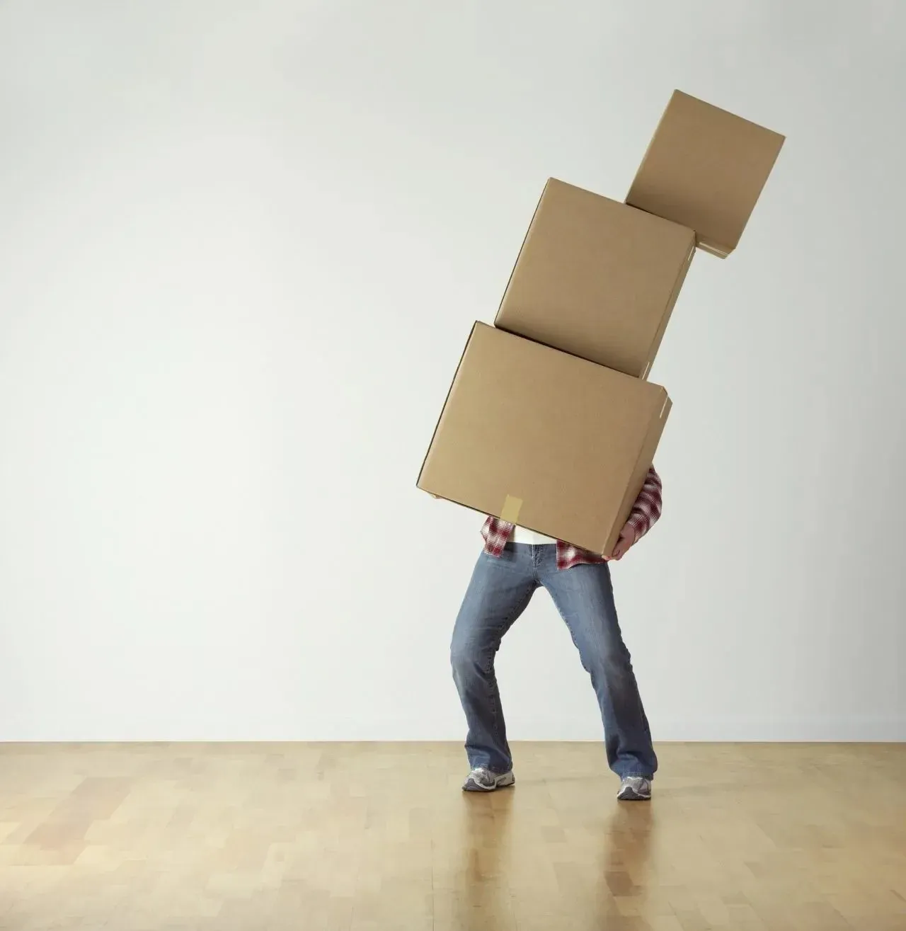 Person carrying tilting stack of three moving boxes