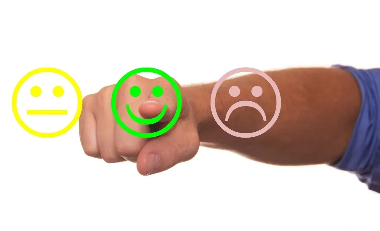 Hand pointing at green smiley face rating option
