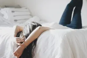 Woman lying on bed, white sheets