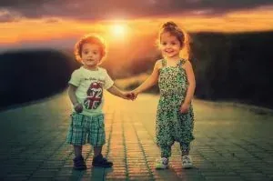 Two kids holding hands at sunset