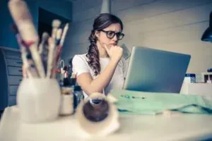 Woman with glasses thinking at laptop