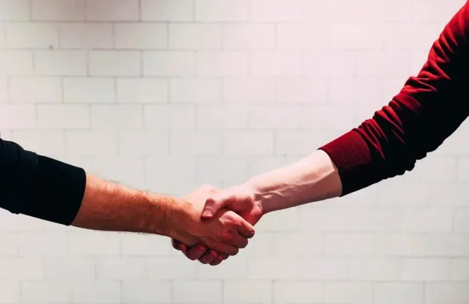 Two people shaking hands against white brick wall
