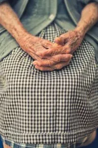 Elderly person's folded hands on lap