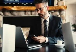 Suited man with phone and laptop