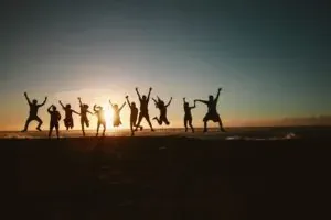 People jumping on beach at sunset
