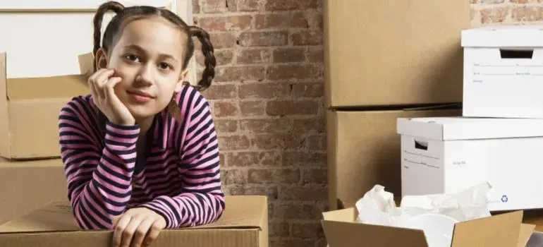 Girl leaning on cardboard boxes near plain file boxes