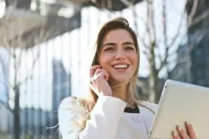 Smiling woman on phone with tablet