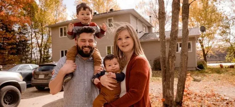 Smiling family of four outside house in autumn