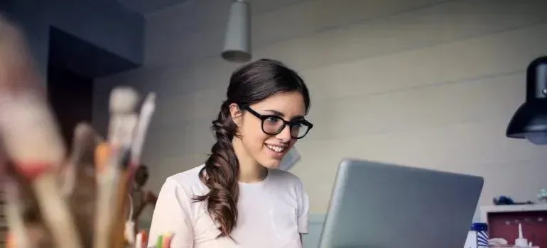 Smiling woman with glasses working on laptop