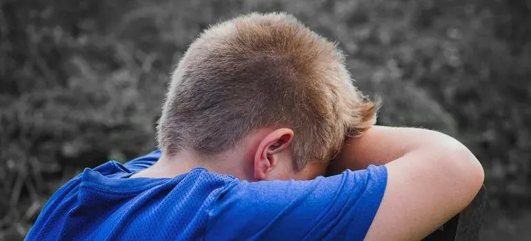 Sad child in blue shirt hiding face
