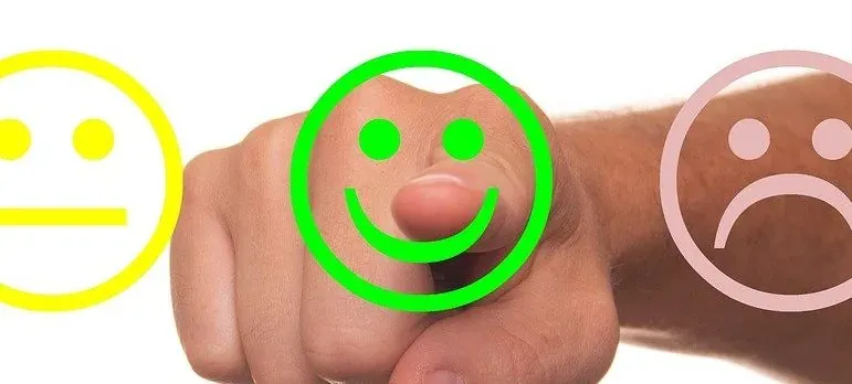 Hand pointing at smiley feedback icons