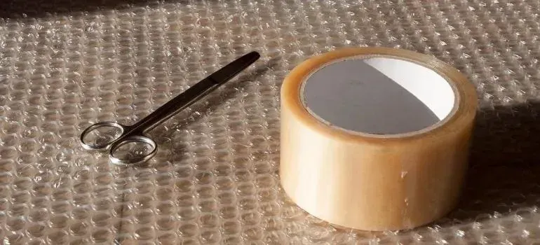 Scissors and packing tape roll on bubble wrap