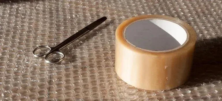 Scissors and packing tape roll on bubble wrap