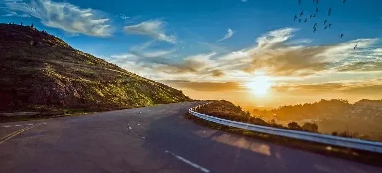 Winding mountain road with guardrail at sunset