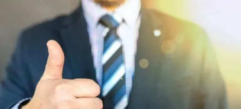 Businessman in suit and striped tie giving thumbs up
