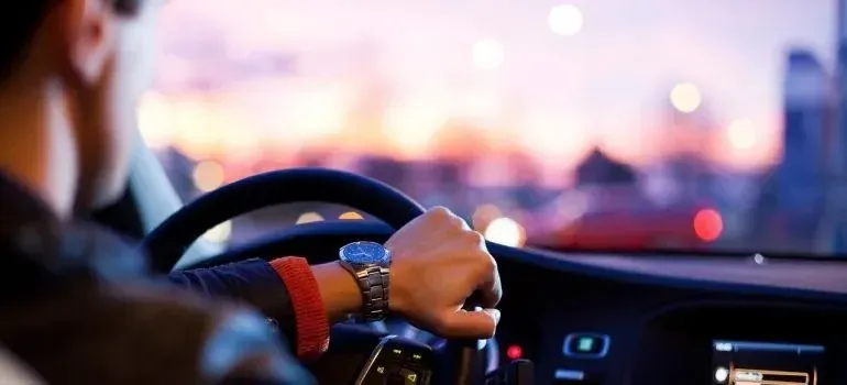 Driver checking wristwatch at wheel, blurred city lights