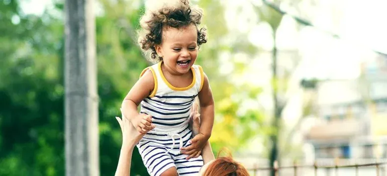 Laughing toddler lifted outdoors