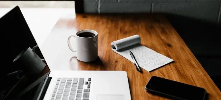 Laptop, coffee, notepad on desk