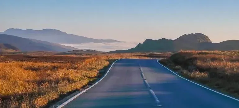 Empty road winding through golden hills at sunrise