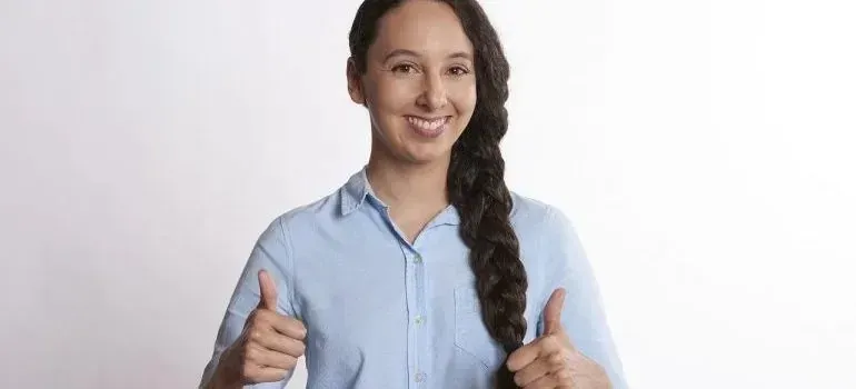 Smiling woman in plain blue shirt giving thumbs up