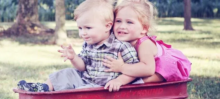 Two toddlers in red toy wagon