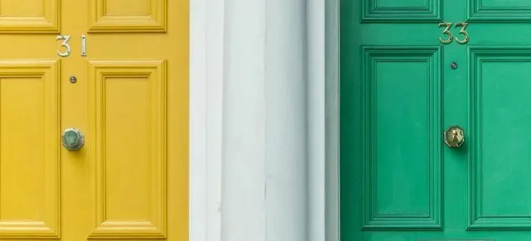 Neighboring yellow and green front doors, numbers 31 and 33