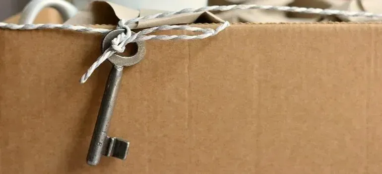 Old key tied with twine to a cardboard moving box