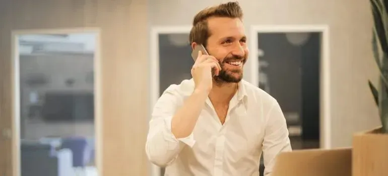 Smiling man in white shirt talking on phone in office