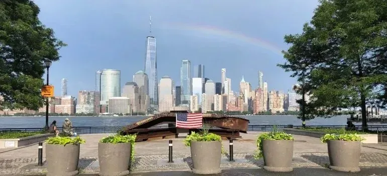 Lower Manhattan skyline with rainbow, American flag, and memorial