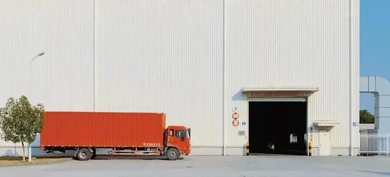 Unbranded orange cargo truck parked at warehouse loading door