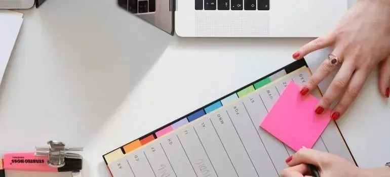 Hands with weekly planner and laptop; small Stabilo highlighter label visible