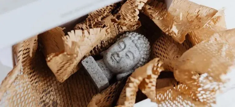 Buddha figurine nestled in shredded packing paper inside box