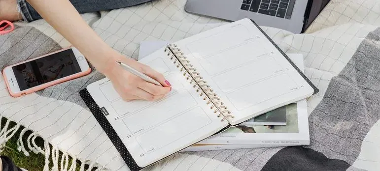 Hand writing in planner on blanket
