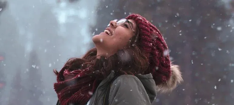 Smiling woman in snow, red beanie