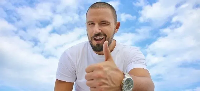Winking man in white tee giving thumbs up outdoors