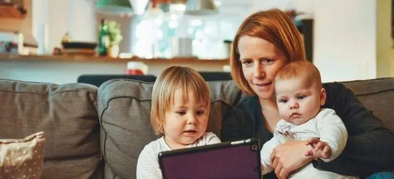 Mother and two young children watching tablet on sofa