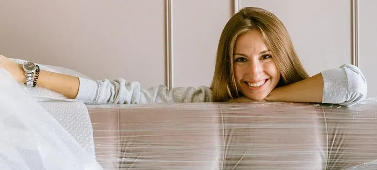 Woman leaning on plastic-wrapped mattress