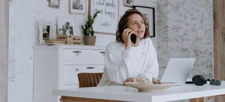 Woman talking on phone at desk in white home office