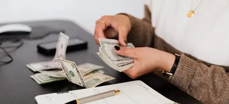 Woman counting dollar bills at desk with planner
