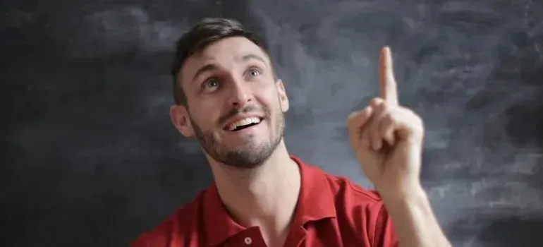 Smiling man in red polo pointing upward