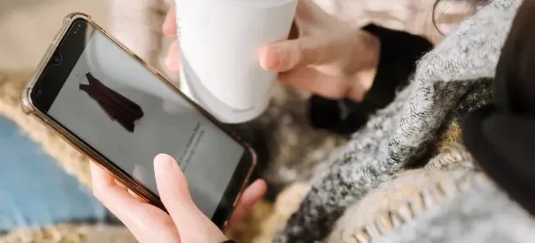 Person with coffee cup shopping on smartphone