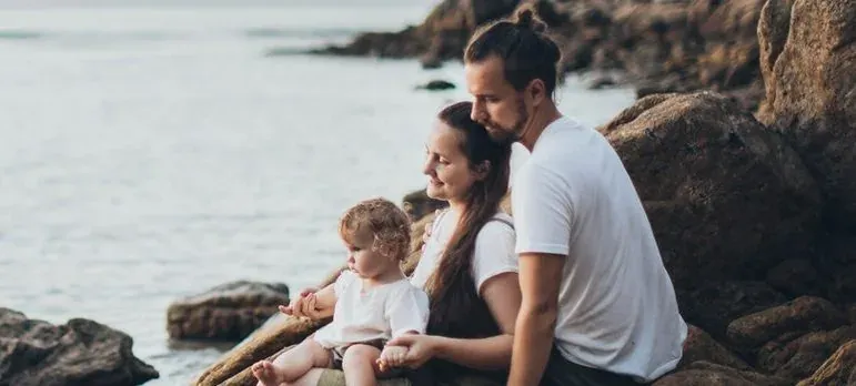 Family with baby on rocky seashore