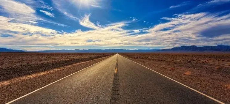 Straight desert highway stretching to horizon under clouds